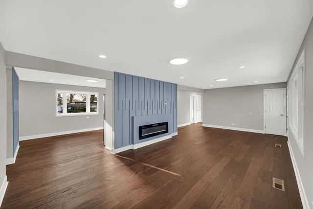an empty room with wooden floor fireplace and windows