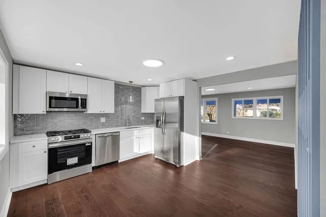 a kitchen with stainless steel appliances granite countertop a refrigerator a stove top oven a sink and dishwasher