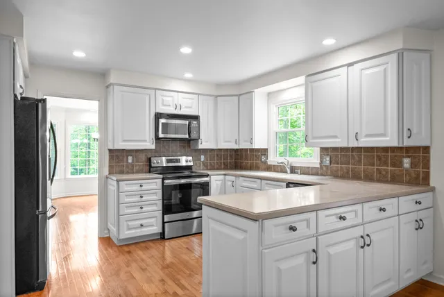 an empty room with windows and chandelier fan
