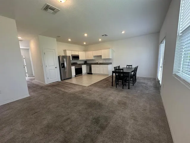 a kitchen with granite countertop a refrigerator and white cabinets