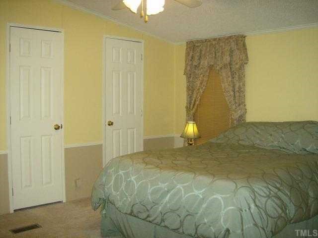 449 Wintergreen Road Timberlake, NC 27583 - Photo 8 of 12 a bedroom with a bed and a chandelier