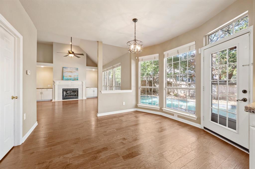 2504 Springhill Drive Grapevine, TX 76051 - Photo 12 of 32 Unfurnished dining area with vaulted ceiling, dark wood-style floors, a chandelier, a fireplace with flush hearth, and a ceiling fan