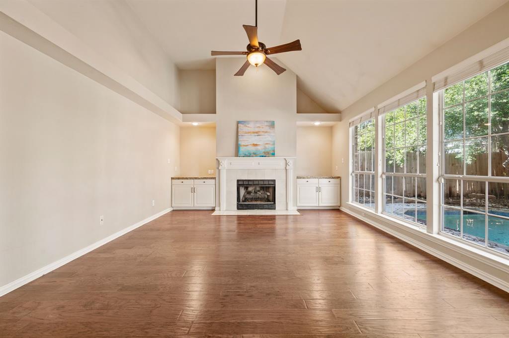 2504 Springhill Drive Grapevine, TX 76051 - Photo 13 of 32 Unfurnished living room with high vaulted ceiling, dark wood finished floors, a tiled fireplace, and a ceiling fan