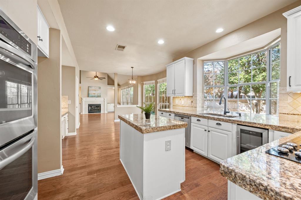 2504 Springhill Drive Grapevine, TX 76051 - Photo 32 of 32 Kitchen with appliances with stainless steel finishes, white cabinets, a kitchen island, open floor plan, and a fireplace