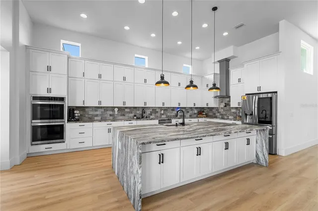 a large white kitchen with stainless steel appliances granite countertop a stove and a sink