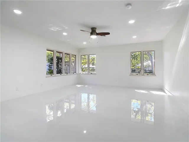 an empty room with windows and ceiling fan