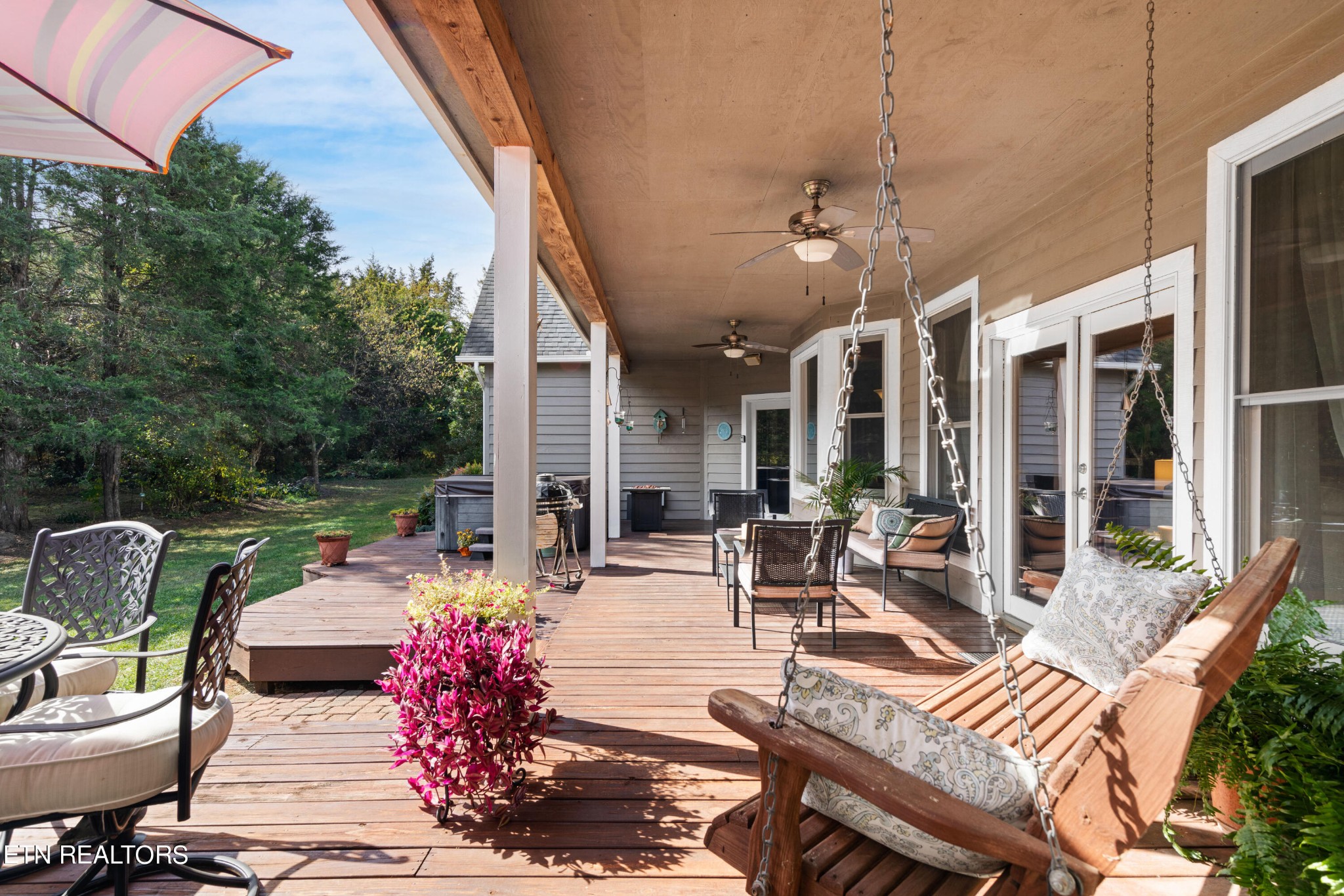 1443 West Dumplin Valley Road Dandridge, TN 37725 - Photo 40 of 51 a view of a patio with dining table and chairs couches with wooden floor and fence