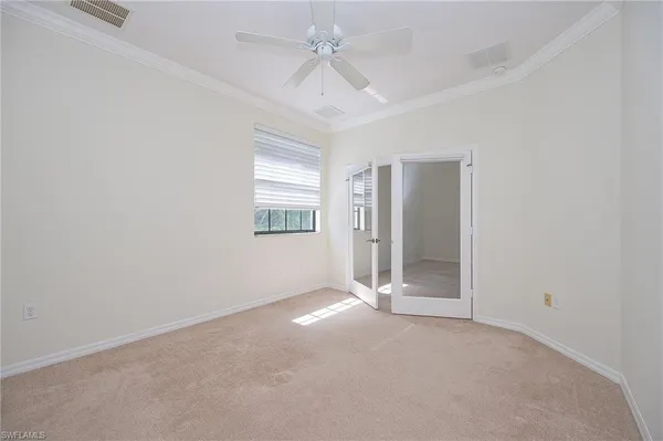 an empty room with a chandelier fan and windows