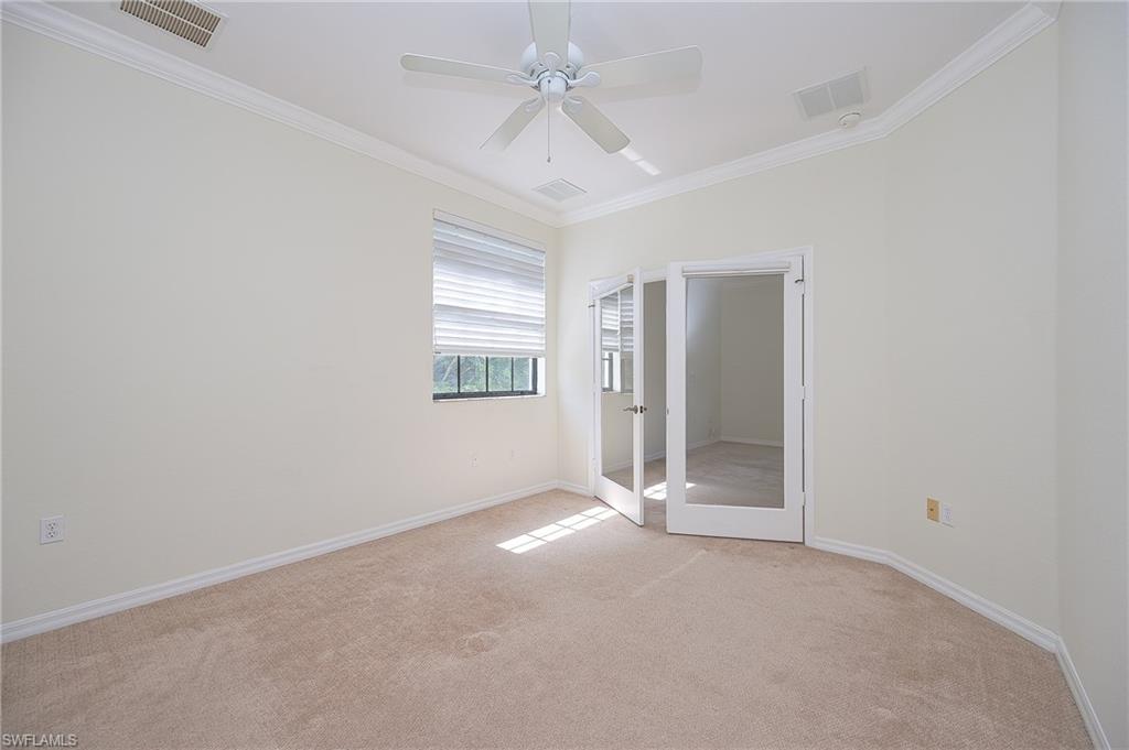 15056 Summit Pl Circle, Unit 228 Naples, FL 34119 - Photo 17 of 27 an empty room with a chandelier fan and windows