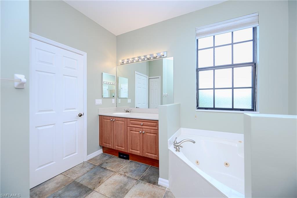 15056 Summit Pl Circle, Unit 228 Naples, FL 34119 - Photo 19 of 27 a bathroom with a tub sink and mirror