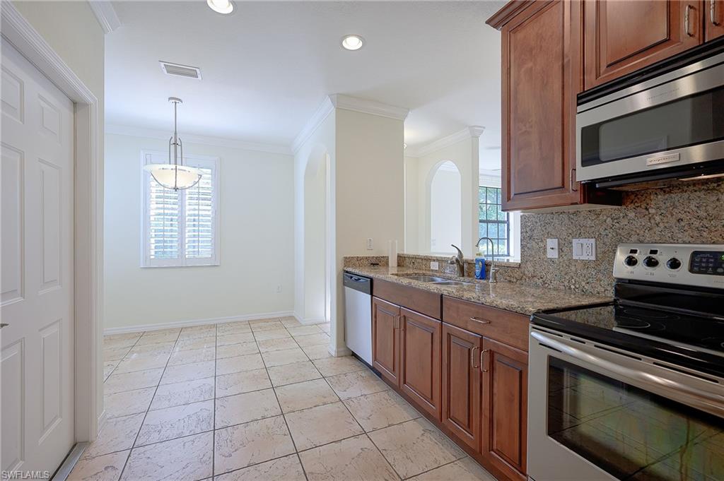 15056 Summit Pl Circle, Unit 228 Naples, FL 34119 - Photo 6 of 27 a kitchen with stainless steel appliances granite countertop a stove a sink and a microwave