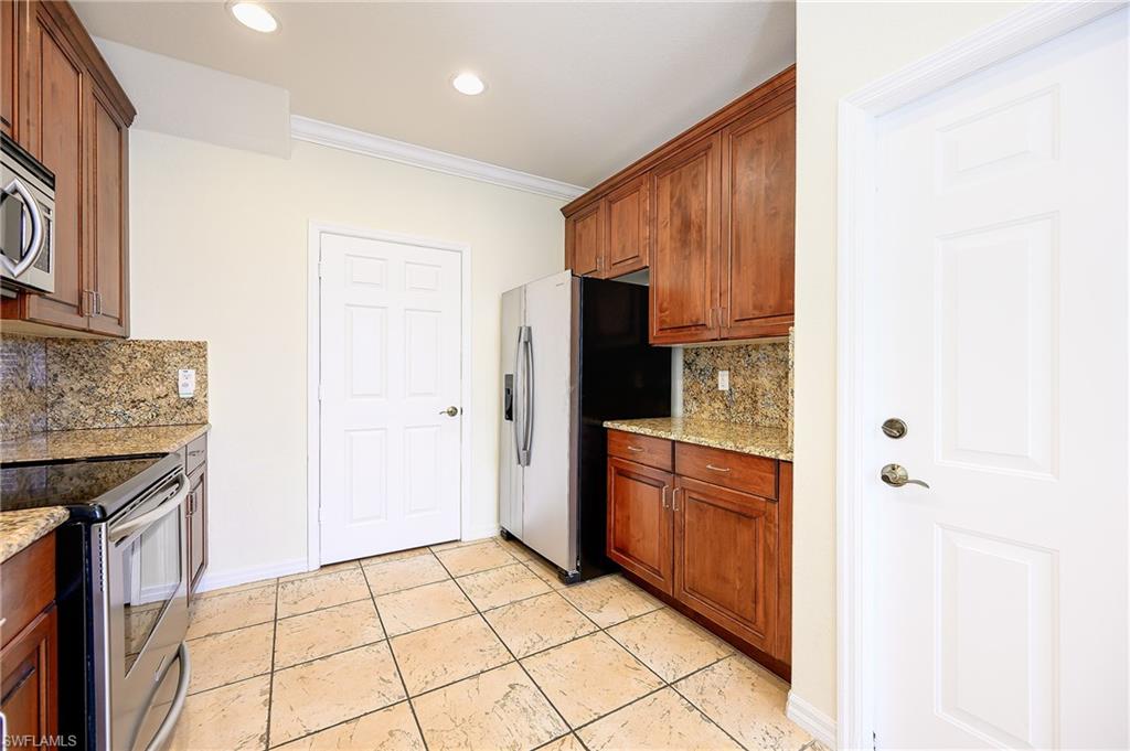 15056 Summit Pl Circle, Unit 228 Naples, FL 34119 - Photo 7 of 27 a kitchen with stainless steel appliances granite countertop a refrigerator and a stove