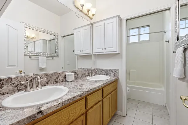 a bathroom with a granite countertop sink and mirror with bathtub
