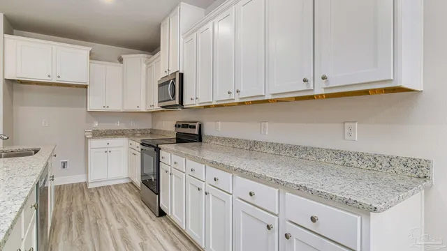 a kitchen with granite countertop a sink dishwasher stove and cabinets with wooden floor