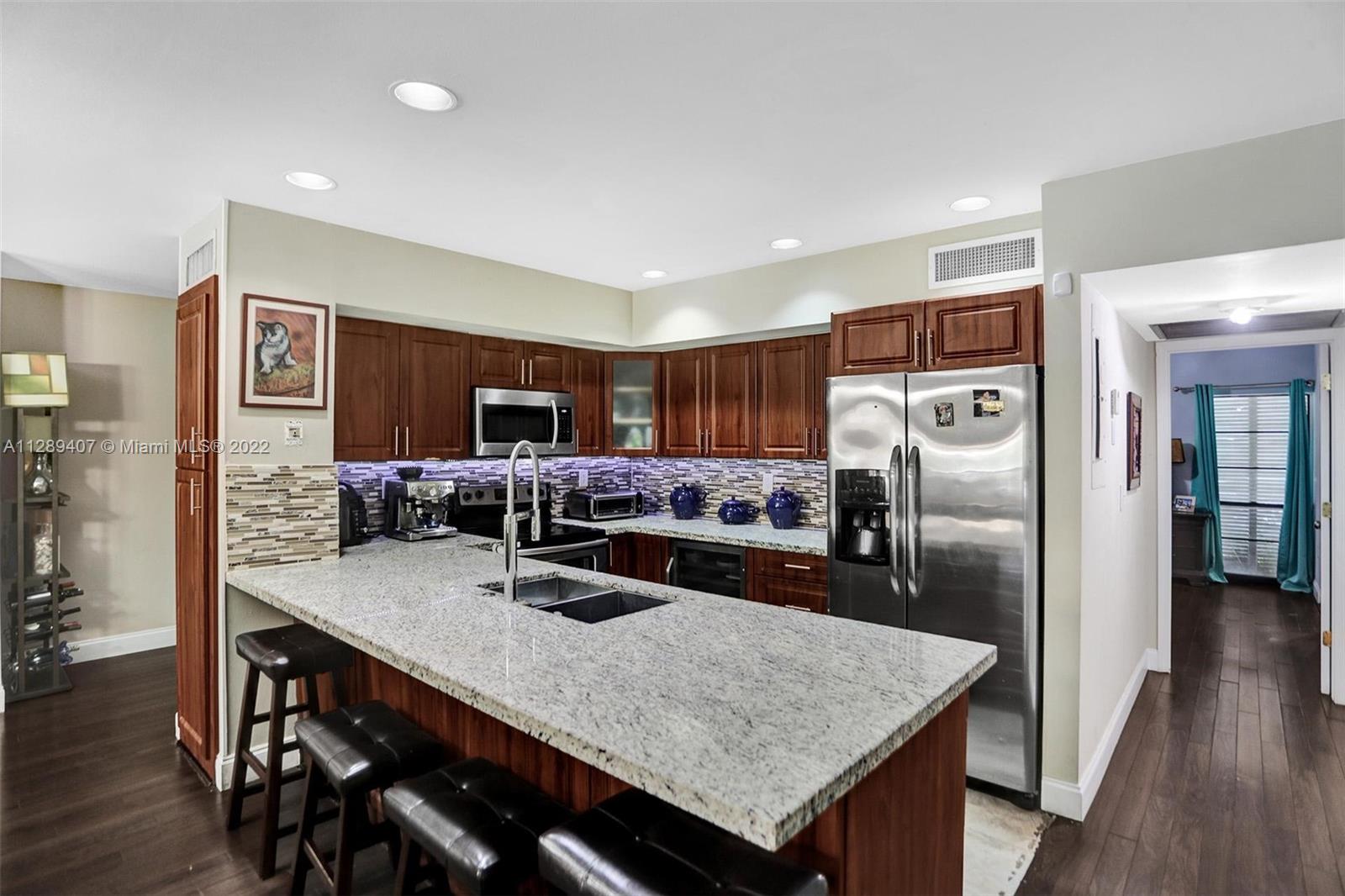 16511 Bridge End Road Miami Lakes, FL 33014 - Photo 17 of 43 a kitchen with a table chairs refrigerator and microwave