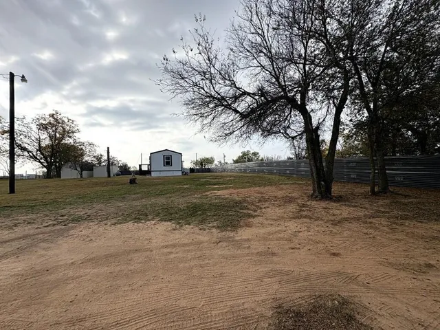 a view of dirt field with trees in the background