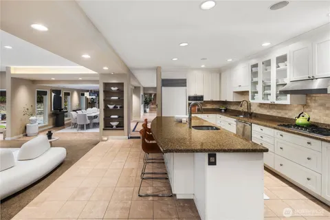 a kitchen with granite countertop a stove a sink a dining table and chairs