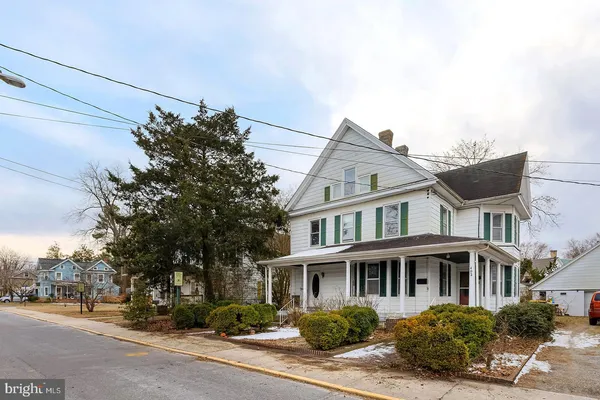 a view of a white house next to a road and yard