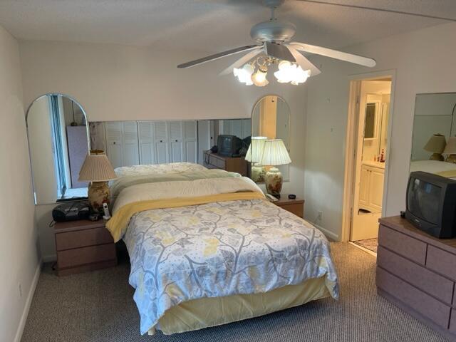 152 Suffolk F Boca Raton, FL 33434 - Photo 10 of 26 a bedroom with a bed a mirror on dresser and a chandelier