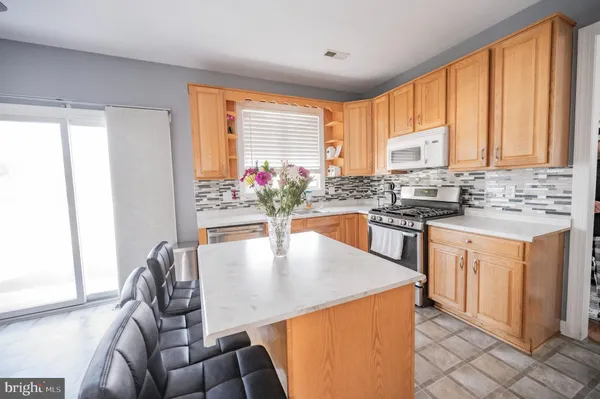a kitchen with stainless steel appliances granite countertop a stove top oven a sink a dining table and chairs