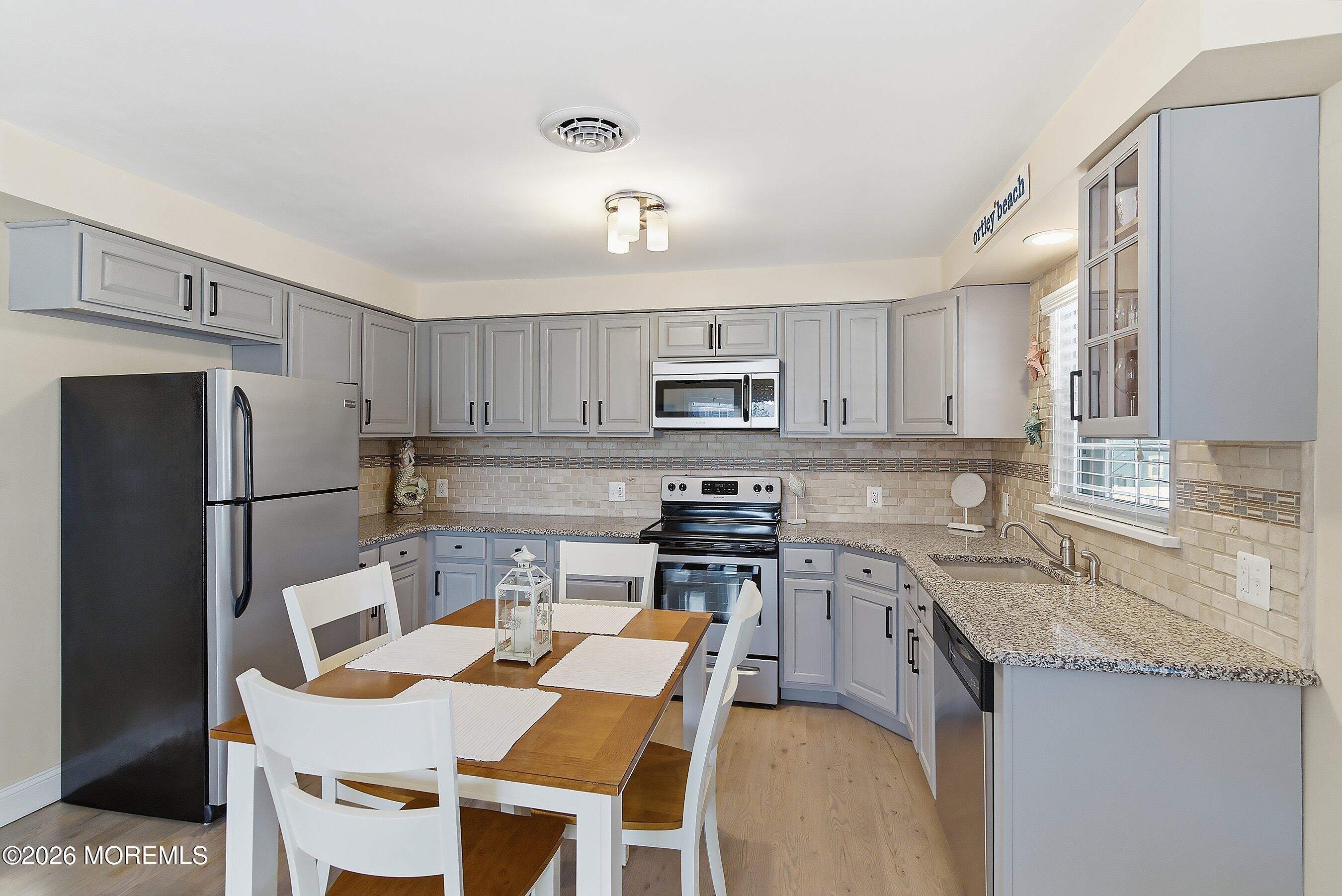 2060 Highway 35, Unit 3 Seaside Heights, NJ 08751 - Photo 9 of 17 a kitchen with stainless steel appliances granite countertop a table chairs sink refrigerator and cabinets