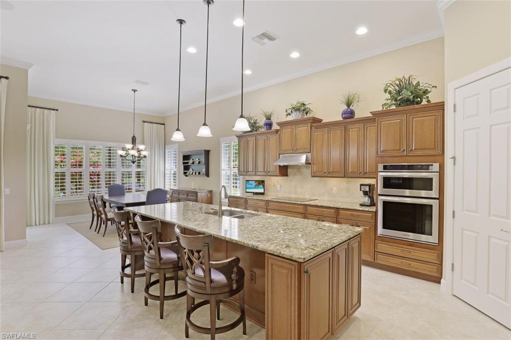 8962 Quarry Drive Naples, FL 34120 - Photo 7 of 35 a kitchen with granite countertop a table chairs stove and kitchen view