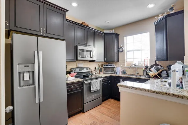 a kitchen with granite countertop stainless steel appliances a sink cabinets and a window