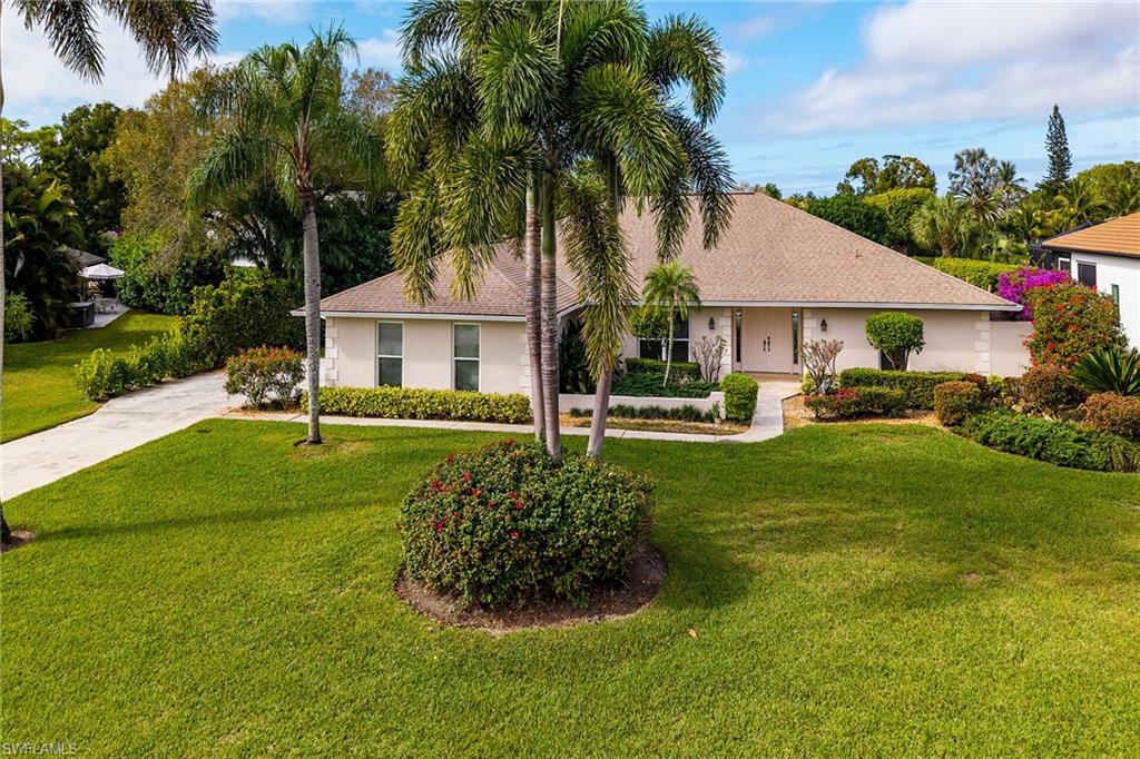 1916 Countess Court Naples, FL 34110 - Photo 14 of 43 a front view of a house with a garden and trees