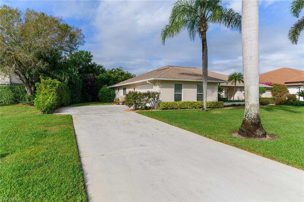 1916 Countess Court Naples, FL 34110 - Photo 2 of 43 a front view of a house with a garden and yard