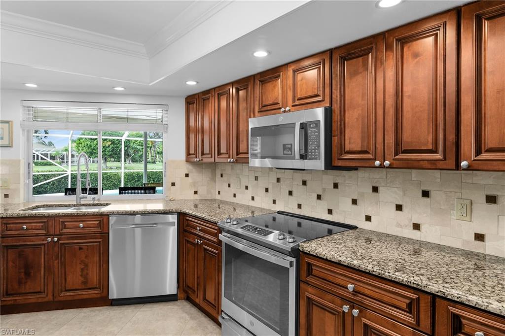 1916 Countess Court Naples, FL 34110 - Photo 32 of 43 a kitchen with stainless steel appliances granite countertop a stove a sink and a microwave