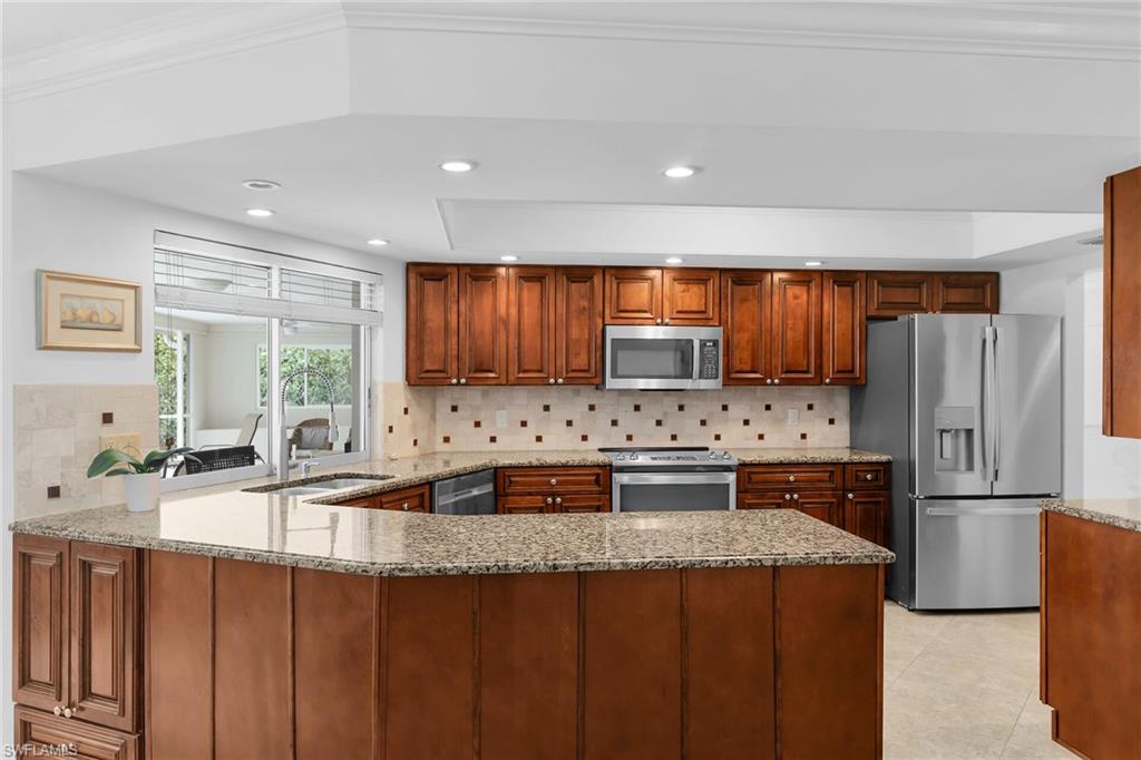 1916 Countess Court Naples, FL 34110 - Photo 35 of 43 a kitchen with stainless steel appliances granite countertop a refrigerator a oven a sink dishwasher and wooden cabinets with wooden floor