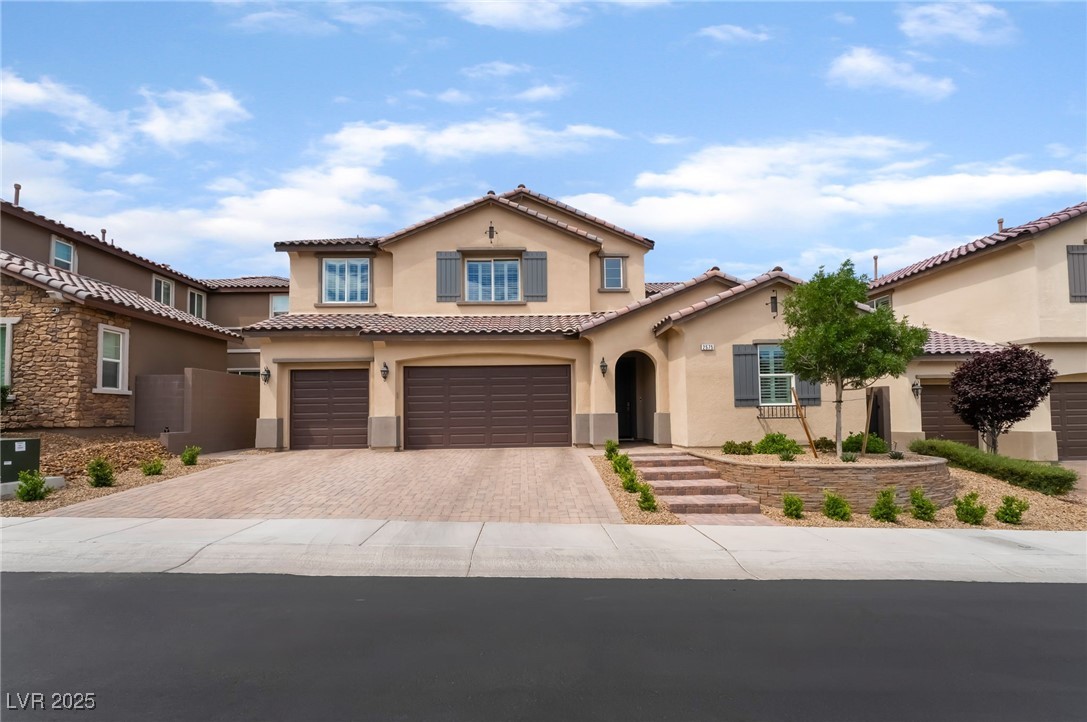 Mediterranean / spanish-style home with stucco siding, decorative driveway, a garage, and a tiled roof