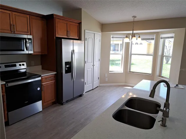 a kitchen with granite countertop stainless steel appliances a refrigerator stove and microwave