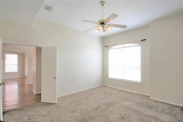 an empty room with chandelier fan and windows
