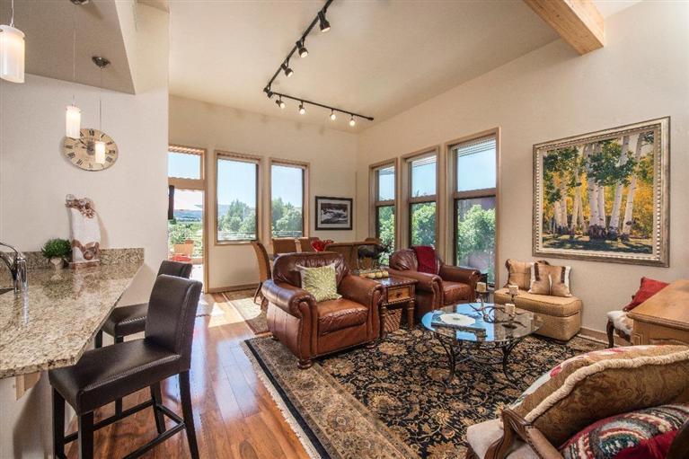 a living room with furniture large windows and wooden floor