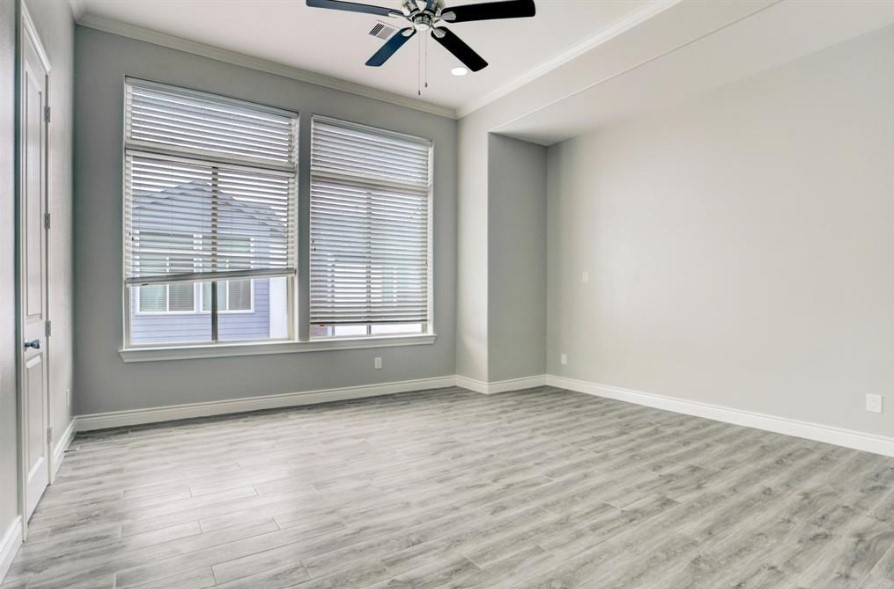 8907 Spring Knoll Forest Drive Houston, TX 77080 - Photo 13 of 21 Primary bedroom on second floor offering contemporary light flooring, a modern ceiling fan, and ample natural light from oversized windows. The room features a clean design with neutral finishes and recessed lighting, offering a blank canvas for personalization.