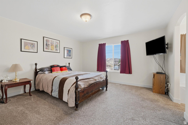 592 West 650 South Springville, UT 84663 - Photo 14 of 33 Spacious carpeted room featuring a ceiling-mounted light fixture, a window with horizontal blinds, and an arched doorway
