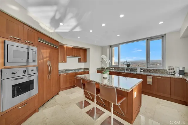 a kitchen with stainless steel appliances granite countertop a stove a sink dishwasher a dining table and chairs with wooden floor