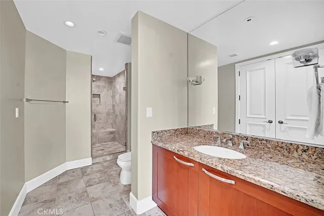 a bathroom with a granite countertop sink a toilet a mirror and shower