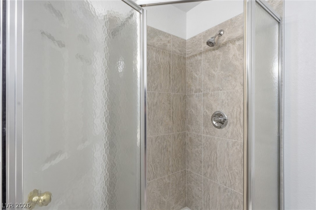 5449 Bugle Way, Unit 104 Las Vegas, NV 89108 - Photo 28 of 33 This sleek shower features modern fixtures and textured wall tiles, creating a contemporary bathroom experience.