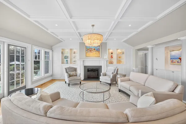 a living room with furniture large windows and wooden floor