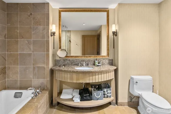 a bathroom with a granite countertop sink a toilet and bathtub