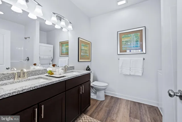 a bathroom with a granite countertop sink vanity mirror and toilet