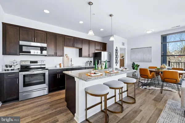 a kitchen with stainless steel appliances granite countertop a stove a sink a microwave a center island and furniture