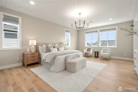 a spacious bedroom with a bed couch chandelier and a window