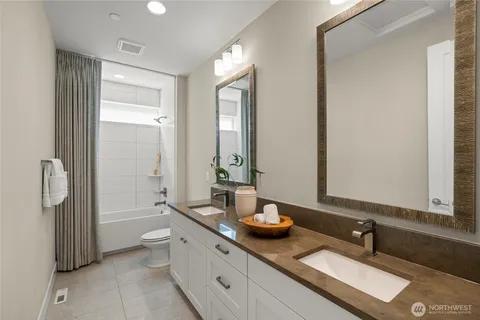 a bathroom with double vanity sinks a toilet and a mirror