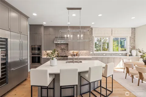 a kitchen with stainless steel appliances a dining table chairs and refrigerator