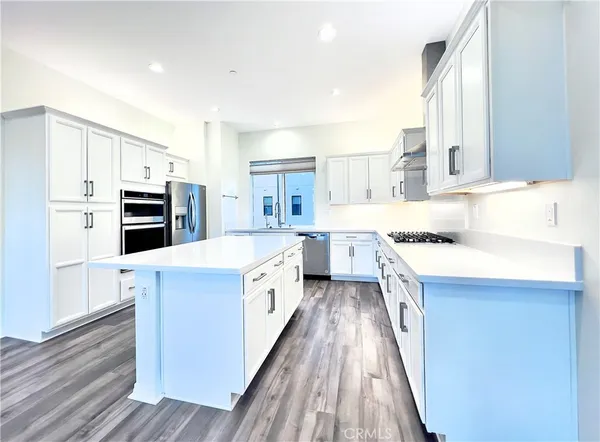a large kitchen with stainless steel appliances granite countertop a large stove a sink dishwasher and a refrigerator with wooden floor