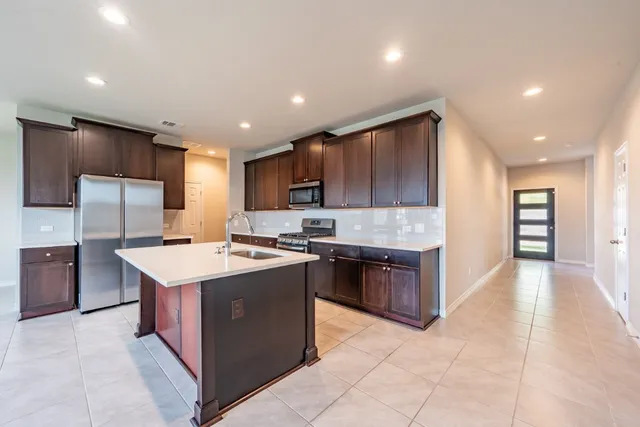 a large kitchen with stainless steel appliances granite countertop a stove a refrigerator a sink a oven and a refrigerator