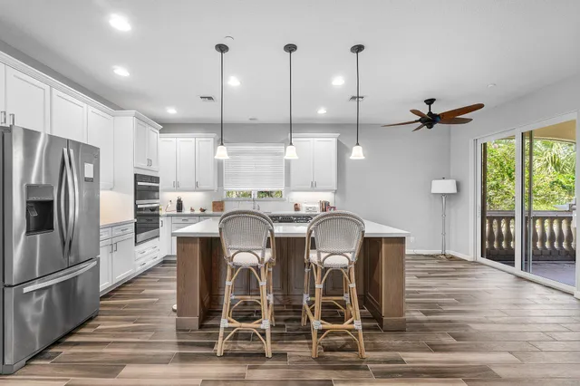 a kitchen with stainless steel appliances granite countertop a dining table chairs refrigerator and microwave